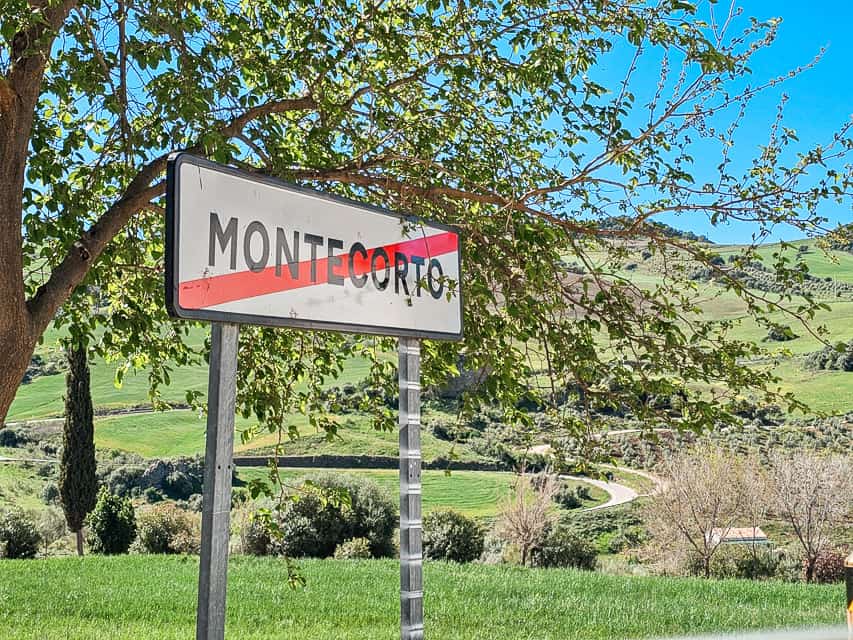 A white sign with the name of the city Montecorto with a red line diagonally through it indicates you are leaving the city.