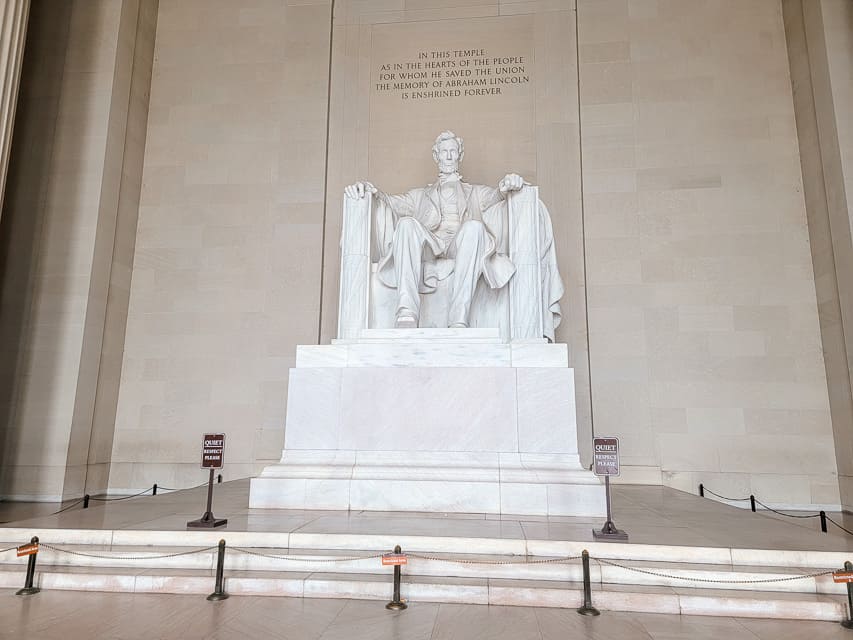 A white stone statue of Abraham Lincoln sitting in a chair is the focal point of the Lincoln Memorial.
