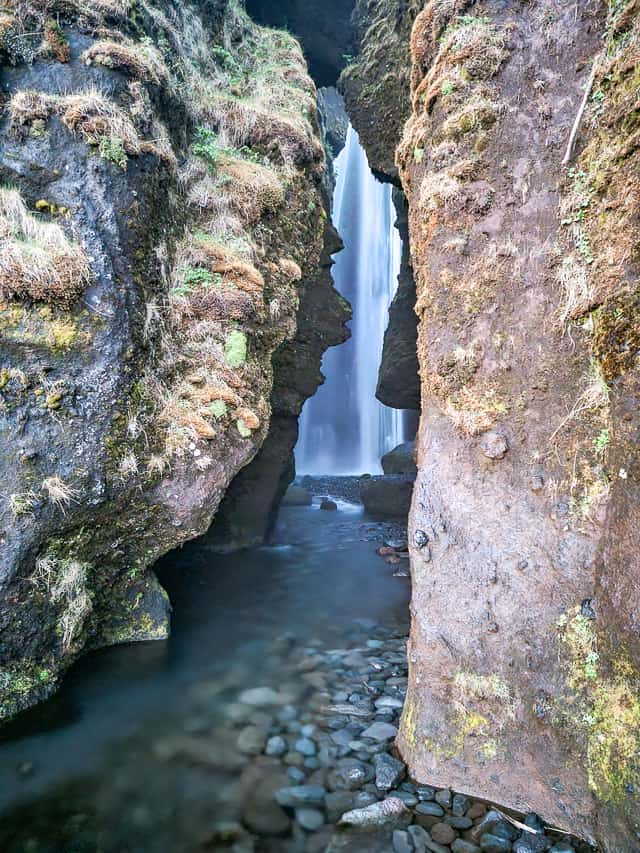 A waterfall cascading between 2 walls of rock.