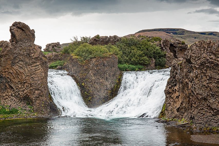 2 twin waterfalls crash down into a very calm pool.