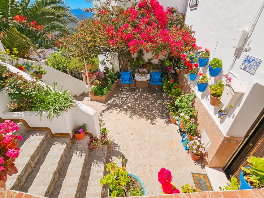 Porch with flowers and chairs with a table.