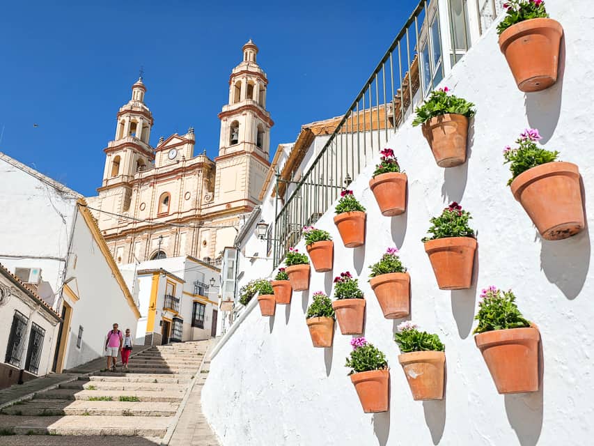 Staircase to church with a wall that has pots and flowers on it.