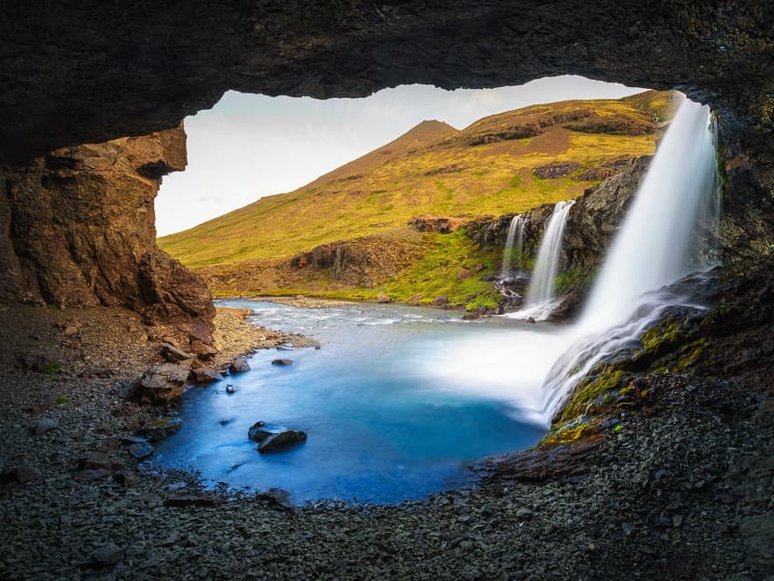 A beautiful view of Skutafoss crashing down the rocks into a deep blue pool.