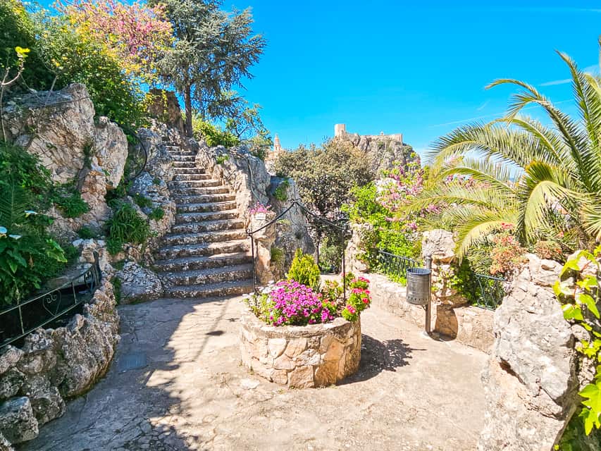 Stone staircase going out from a platform with a well like structure with flowers in it.