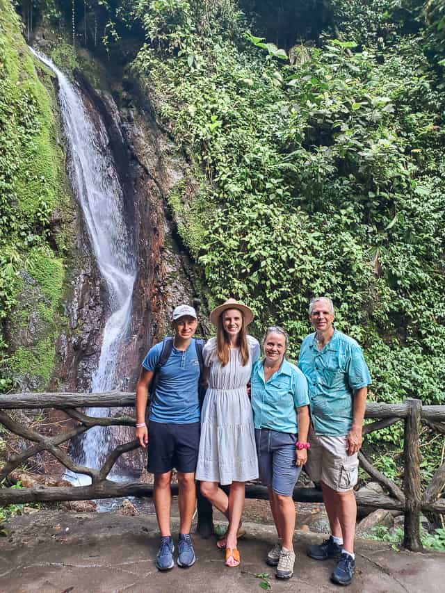 2 women and 2 men stand in front of a waterfall in Mistico hanging bridges park.