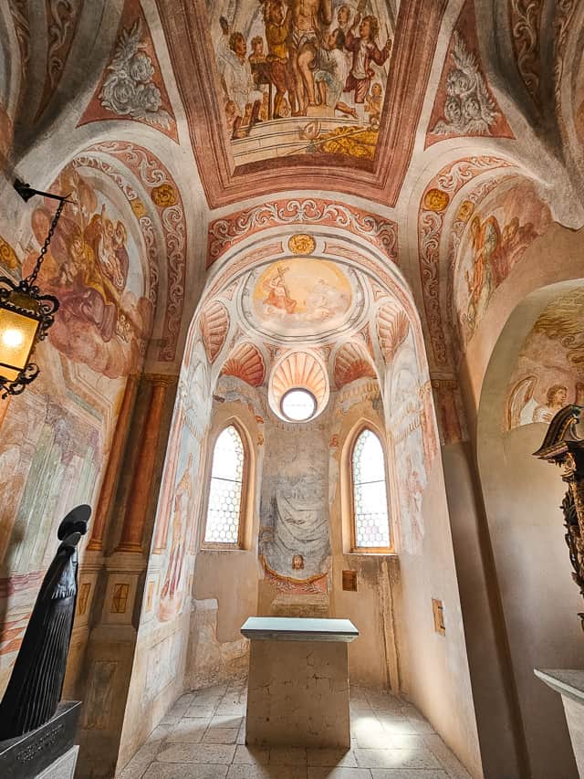 A tall room had multi colored paintings all around the ceilings with pillars shooting down.