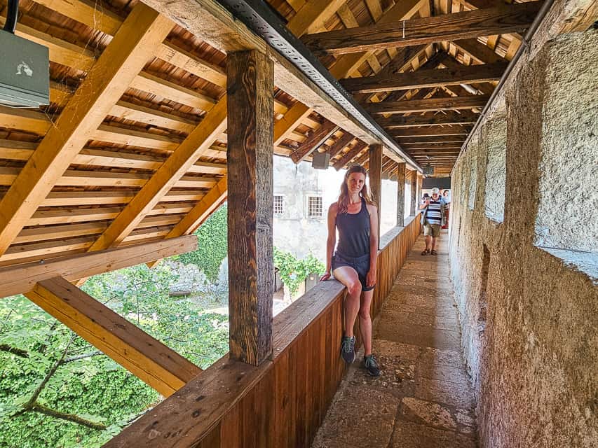 A woman poses on a wood railing on the castle walls.