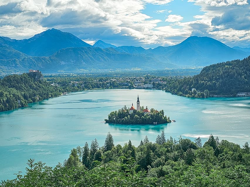 A beautiful overlook of blue Lake Bled with Bled island in the middle and mountains all around it. This is one of the best things to do in the Lake Bled area.