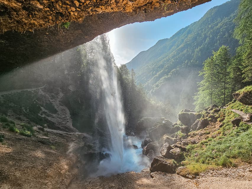 A waterfall falls down into a river with mist everywhere.