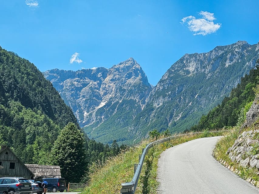 Road turns around the corner with mountains and trees everywher.