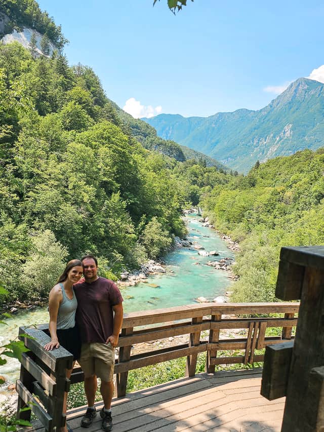 A man and woman stand together with the views of the turquoise Soča River in the background.