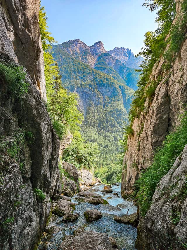 River, with tall cliff walls on both sides, runs out towards mountains.