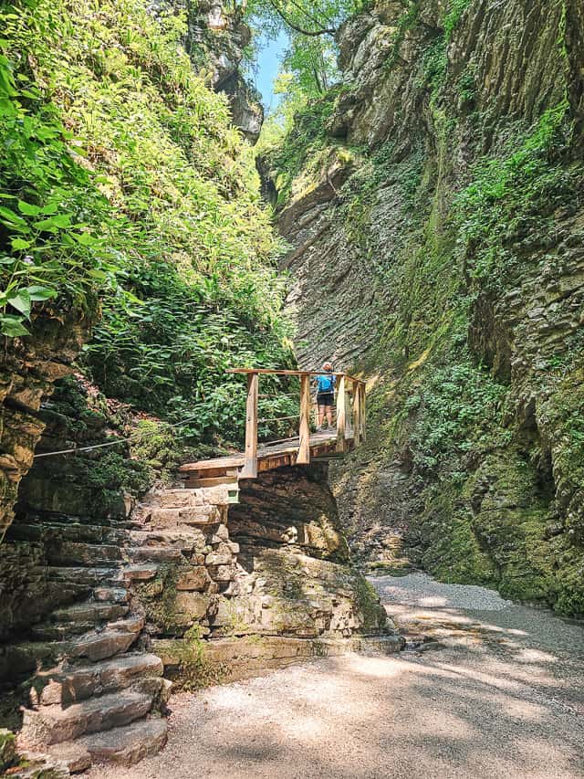 A stone staircase leads to a wood bridge and walkway along the side of a cliff near Slap Kozjak.