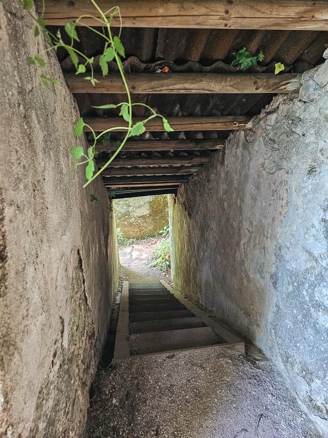 Stone stairs lead through a WW1 bunker located near Slap Kozjak, with a wood and metal roof.