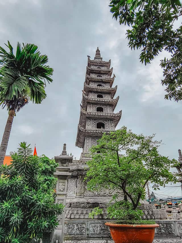 An asian stone building with lots of markings and etchings carved into the sides and overhangs on different levels of the building.