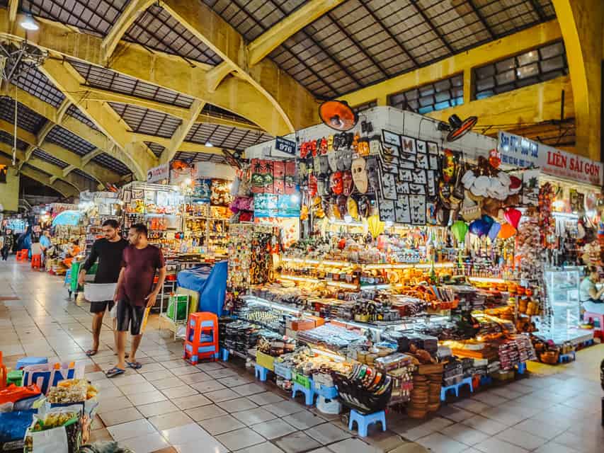 A busy market with lit up stands with all sorts of souvenirs and trinkets.