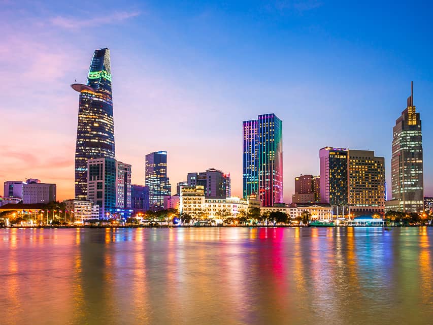 Rainbow colored buildings reflect on the lake with the colors of the sunrise on the glassy water.