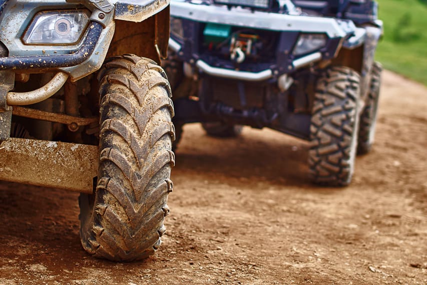 2 blue jeeps with dirt and grime on the tires and front.