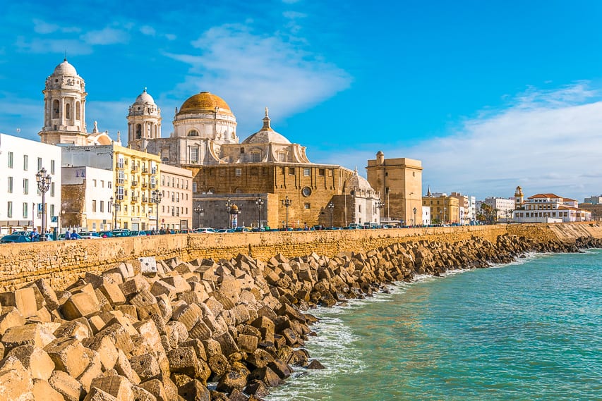A gorgeous spanish coast with rocks and blocks on one side and beautiful spanish white stone buildings.