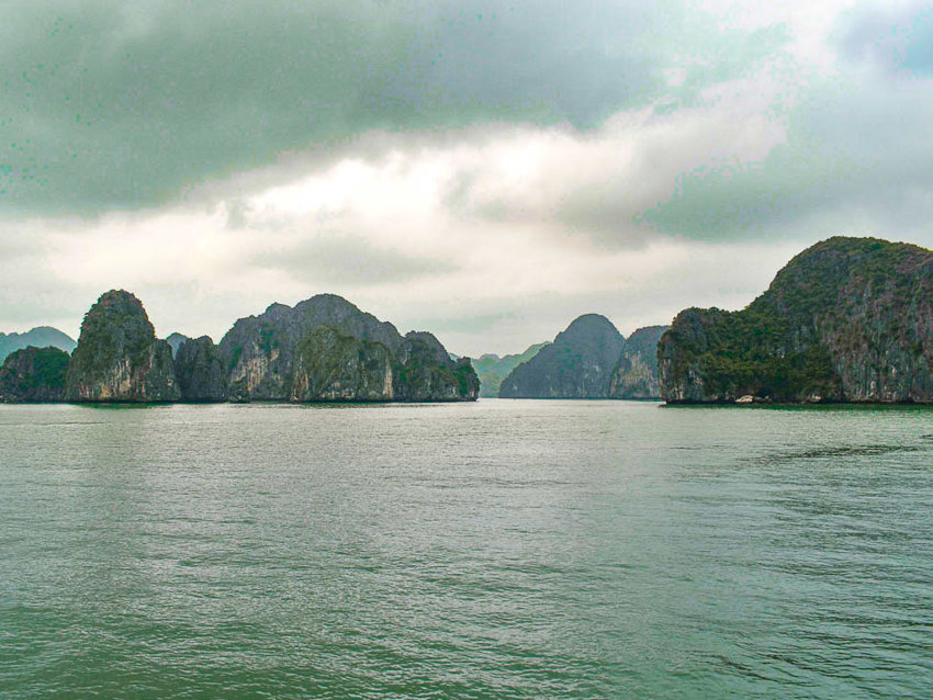 Multiple sheer rock islands scatter around in the blue and round water.