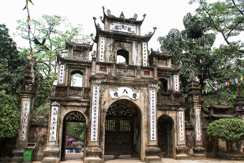 An old stone building with white Vietnamese letters with multiple arches and overhangs.