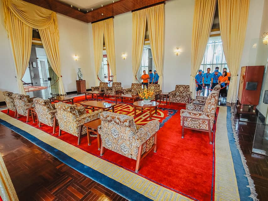 A velvet red and yellow room with detailed chair patterns with a red and blue rug.