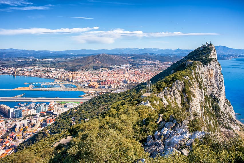 A breathtaking mountain overlooking the deep blue sea and orange and white city.