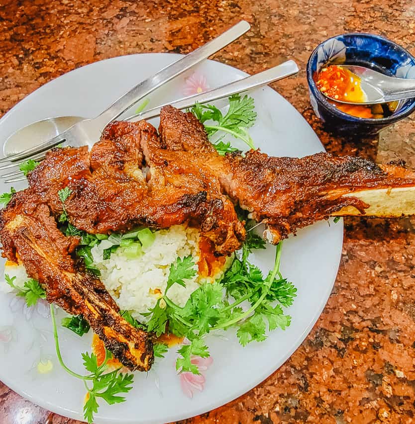 A dish with rice and spinach with a thick juicy red piece of meat.