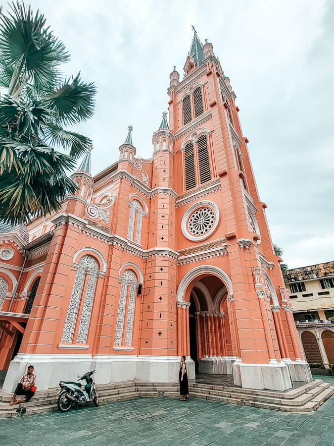 A pink stone church with multiple tiny steeples and one large one.