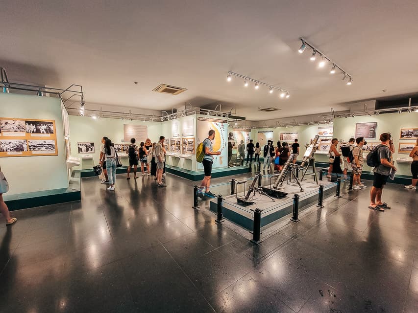 A war museum with different artifacts and tourists in the room.