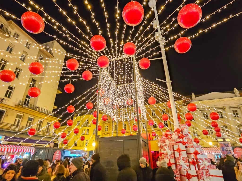 A lit up decoration in the Christmas Market with string lights and red balls decorating the vicinity.
