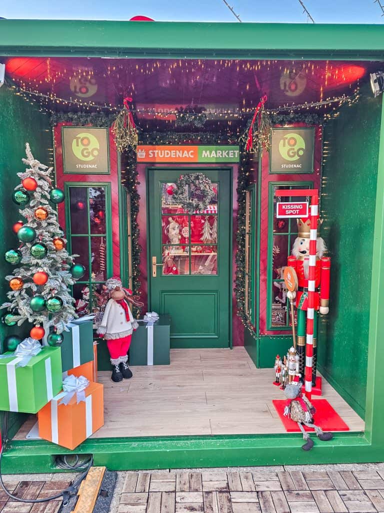 A small green wooden store with the outside decorated with Christmas trees and nutcrackers
