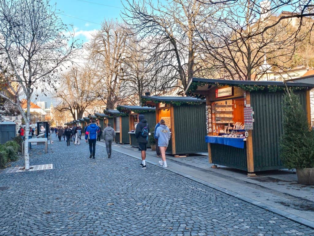A row of small huts with jade green walls selling hot chocolate and different food / souvenirs.
