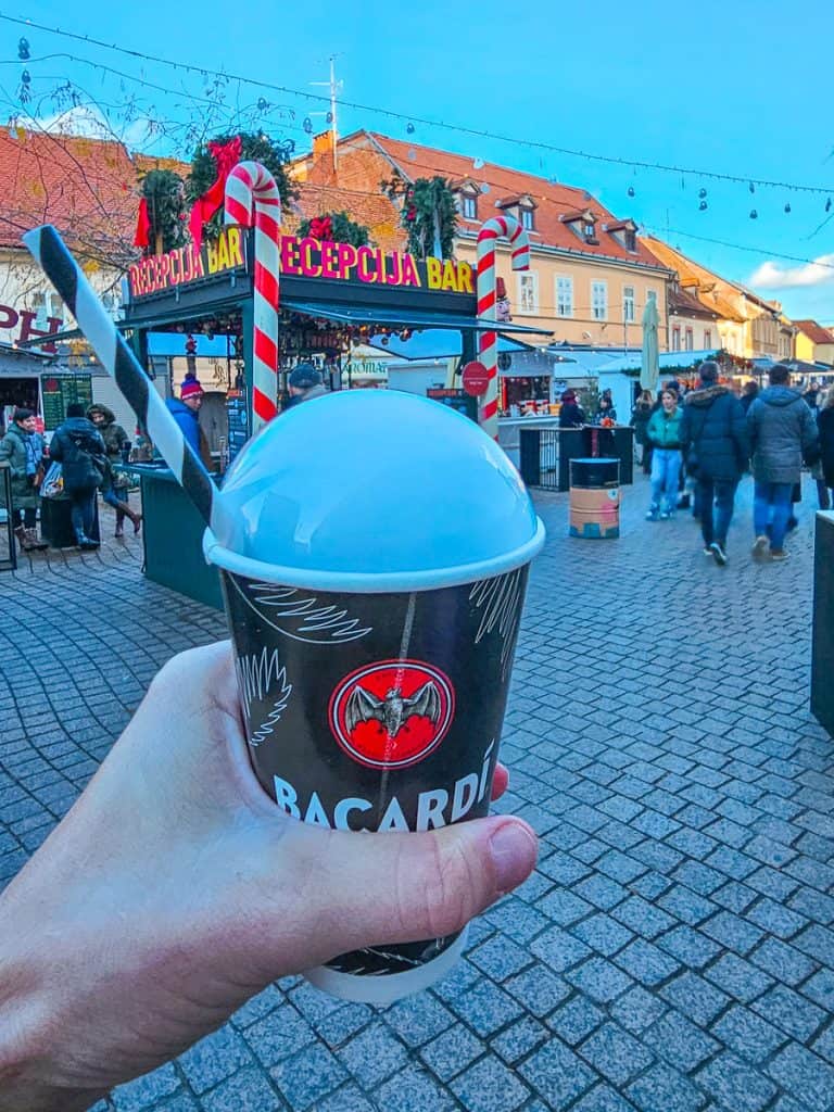 A black and red plastic cup with a straw coming out of the side.