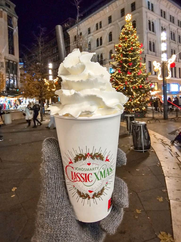 A large white cup of hot chocolate with lots of whipped cream piled up on top.