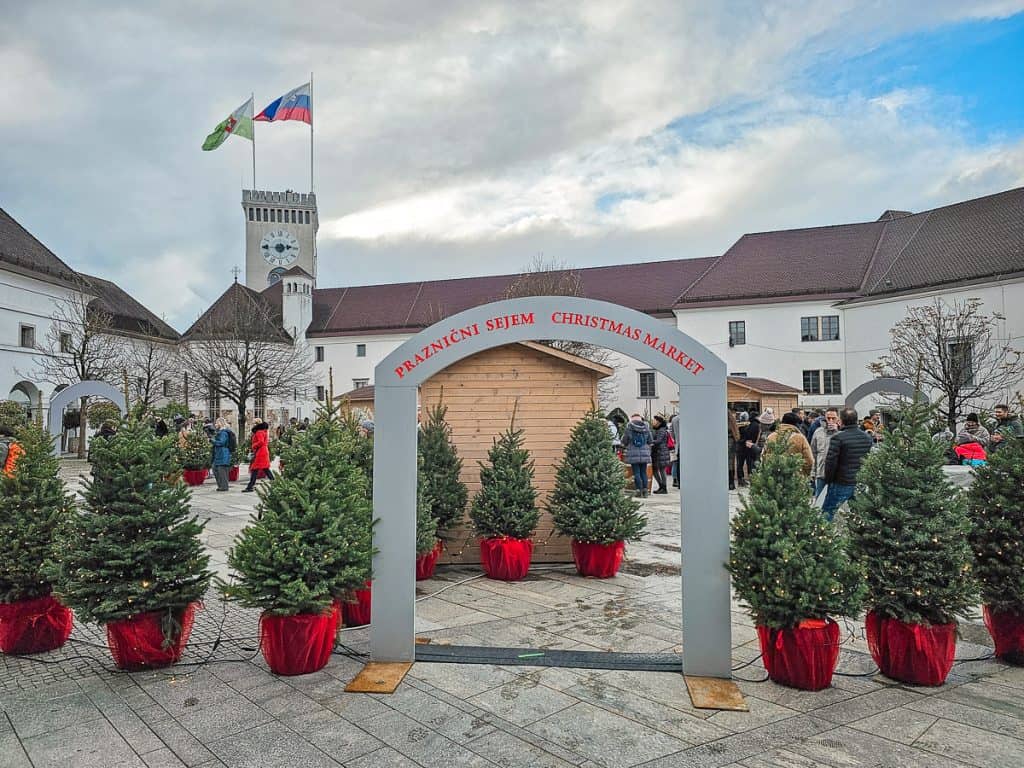 A cute red and grey sign with small christmas trees surrounding it.