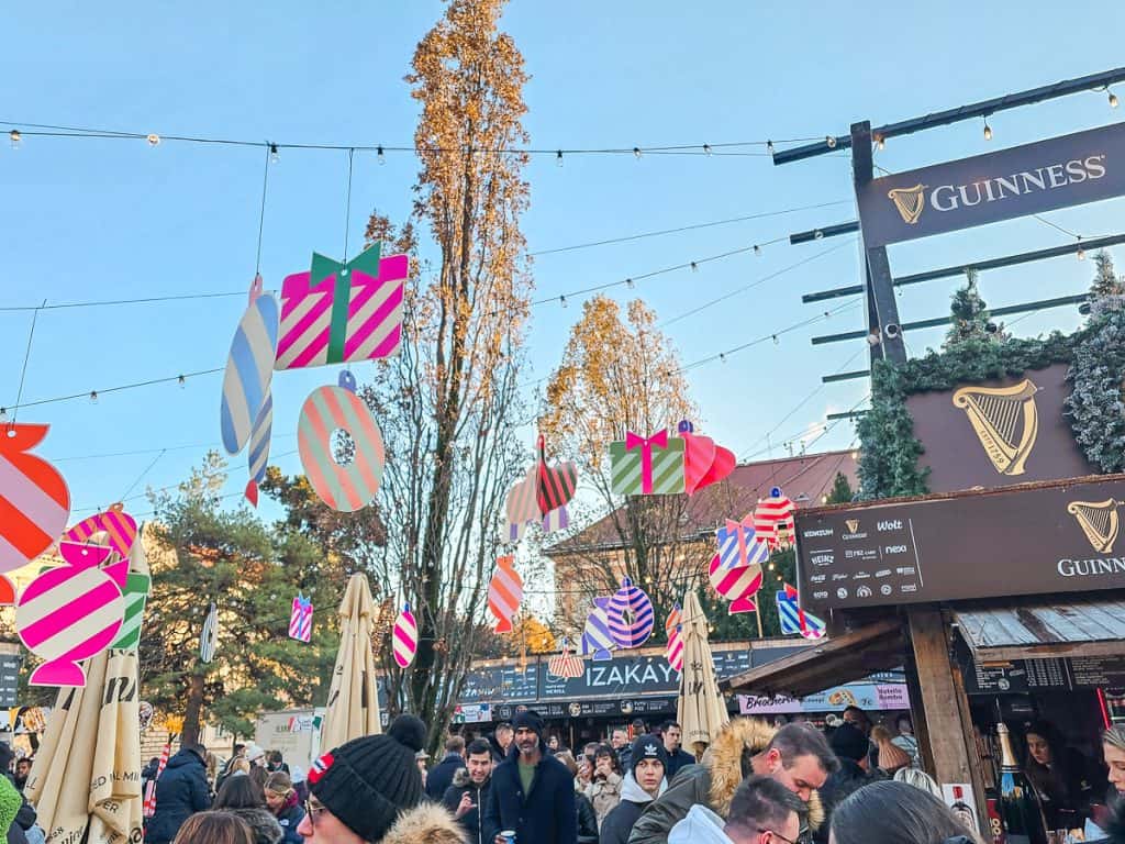 Different colored decorations shaped like presents that are being hung up from booth to booth