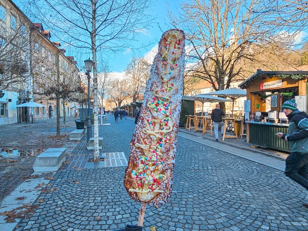 A Slovenian treat a waffle cone in the shape of a tree with multi colored sprinkles and custard